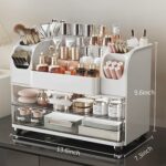 Heaime white acrylic makeup organizer with two drawers and an open top section holding brushes, lipsticks, and skincare bottl