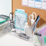 Clear plastic vanity makeup organizer with six compartments, holding various beauty brushes and cosmetic items.