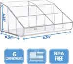 Clear plastic vanity makeup organizer with six compartments, holding various beauty brushes and cosmetic items.