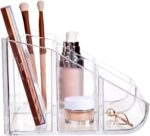 Clear plastic vanity makeup organizer with six compartments, holding various beauty brushes and cosmetic items.