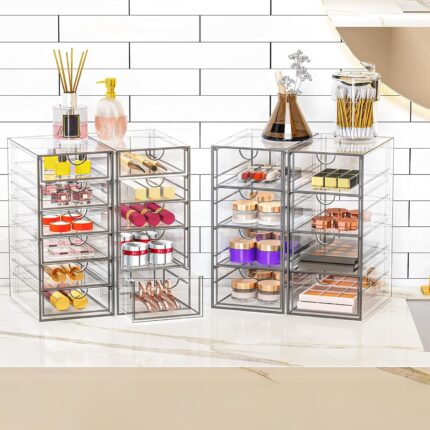 Four clear acrylic makeup organizers stacked and side-by-side, showcasing multiple drawers filled with various cosmetics and